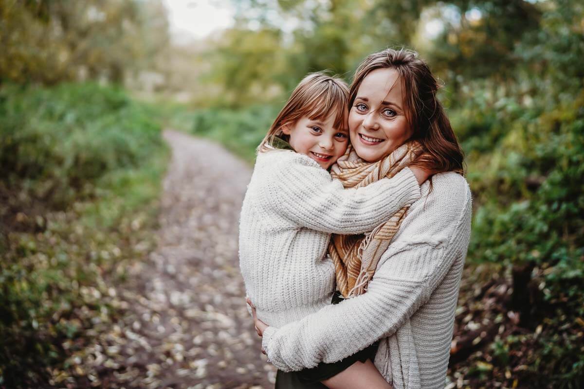 mother and daughter smiling at the camera for an outdoor family photographer in Oxford