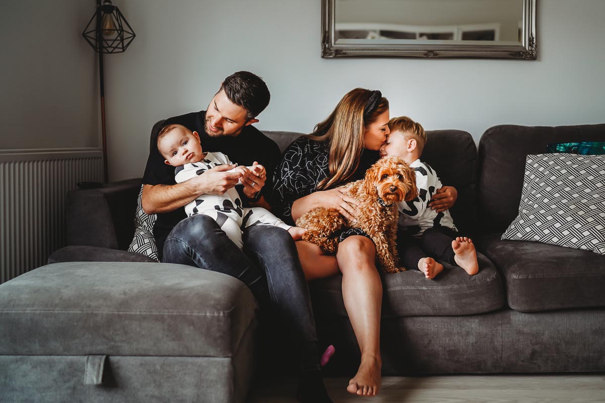 Newborn and his family cuddling on the sofa on an in home photoshoot