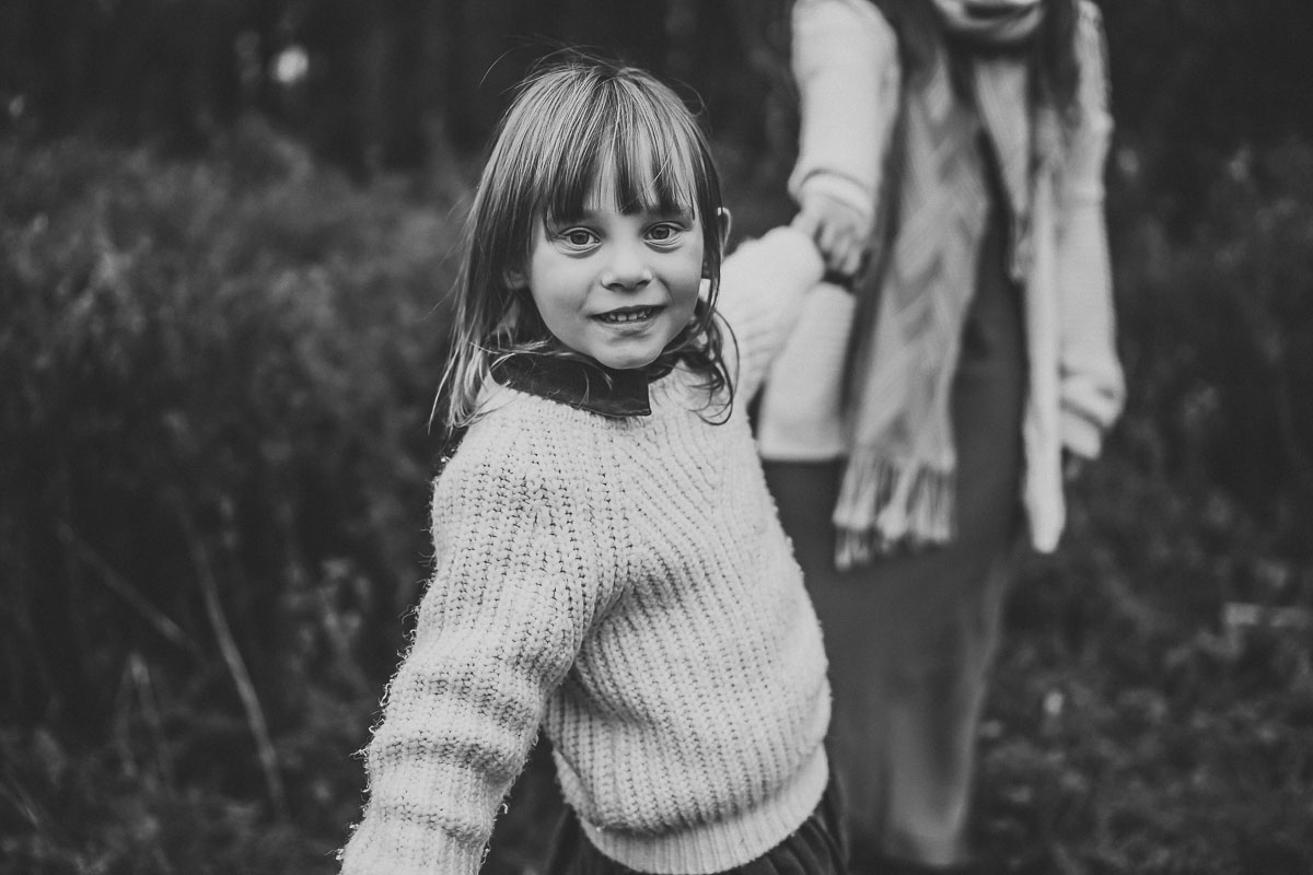 black and white image of a little girl smiling at the camera for an oxford family photographer