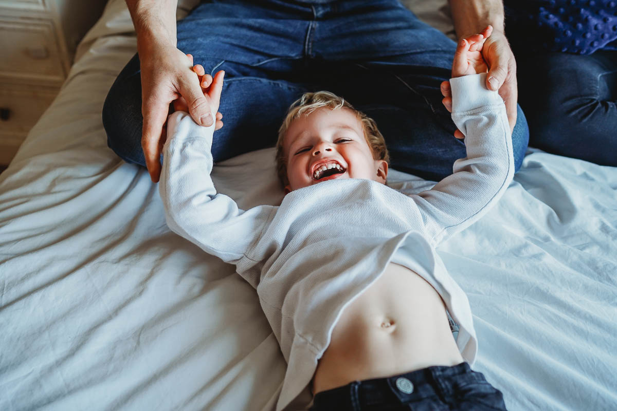 a little boy laughing on a bed during a photoshoot for a Newbury photographer