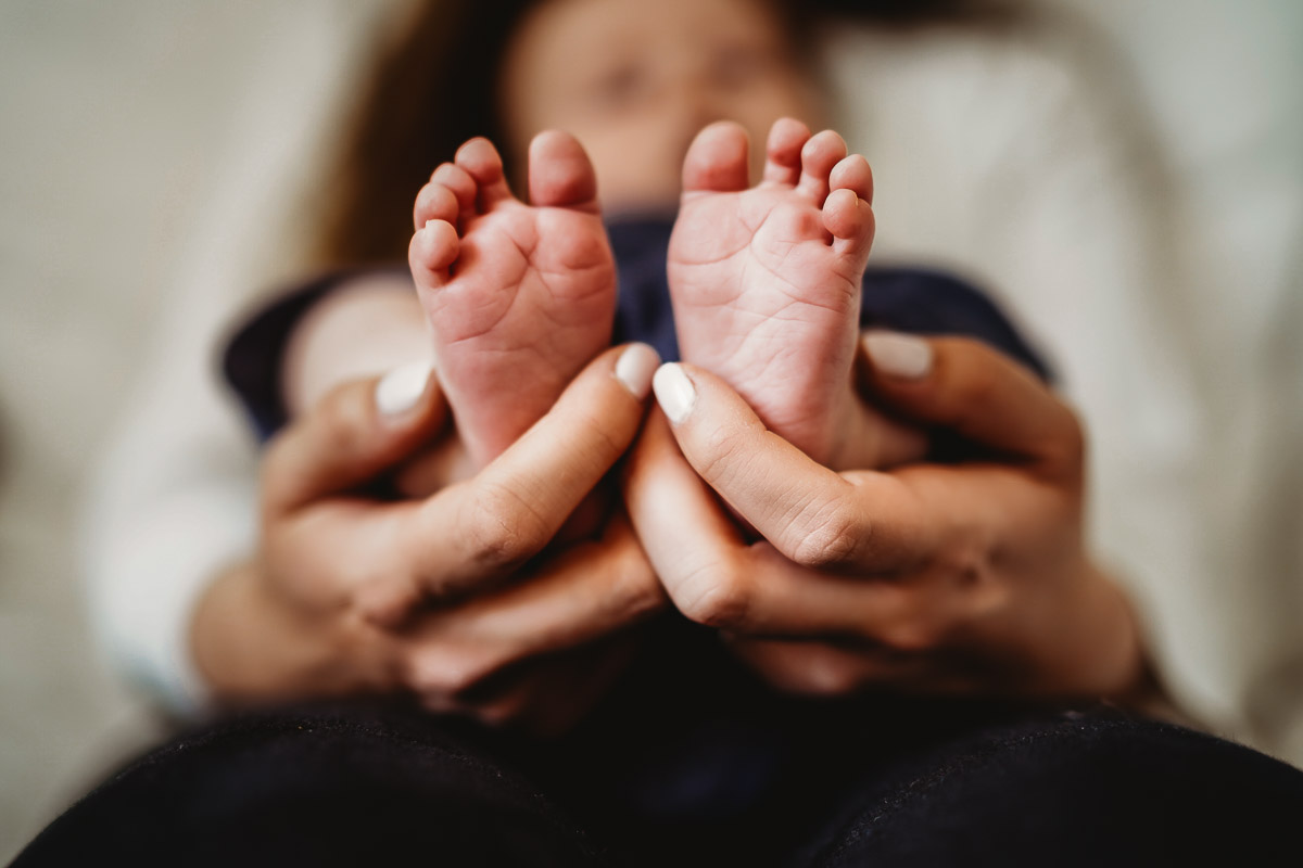 a mother holding her newborns feet for a newbury photographer