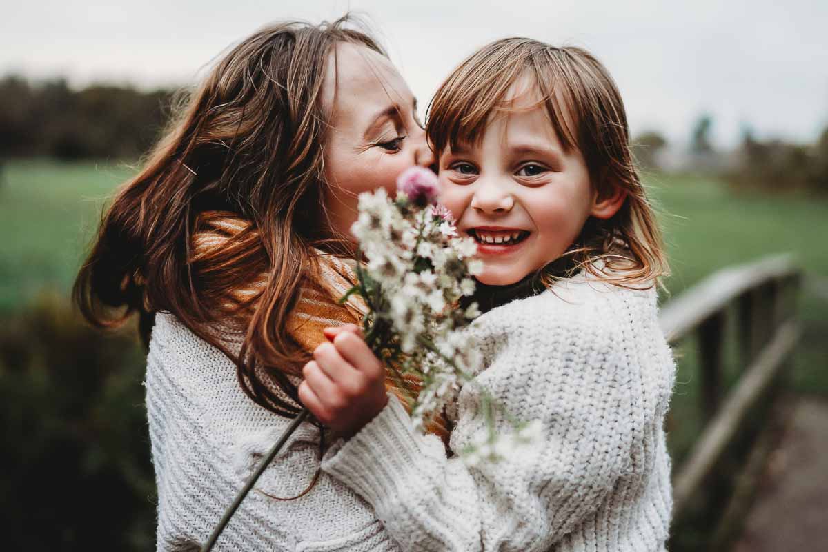 mother and daughter hugging whilst shes holding picked flowers