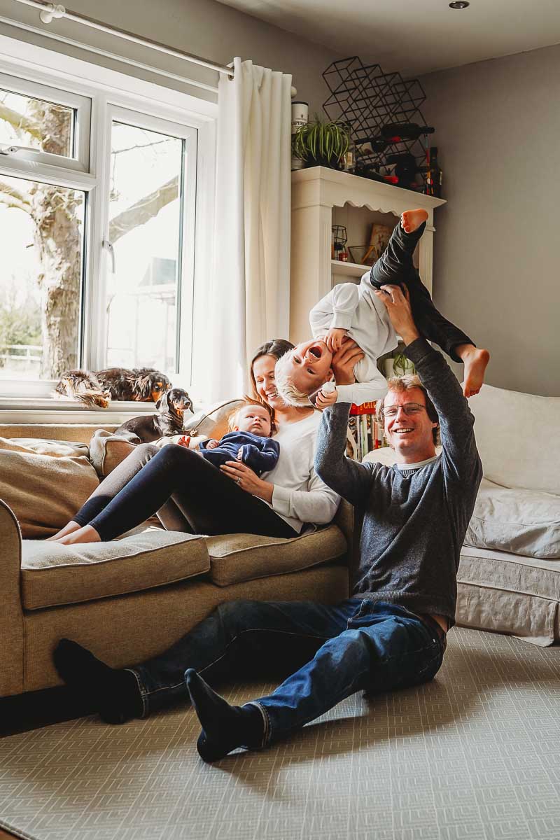 a dad tipping his son upside down during an in home newborn photography session