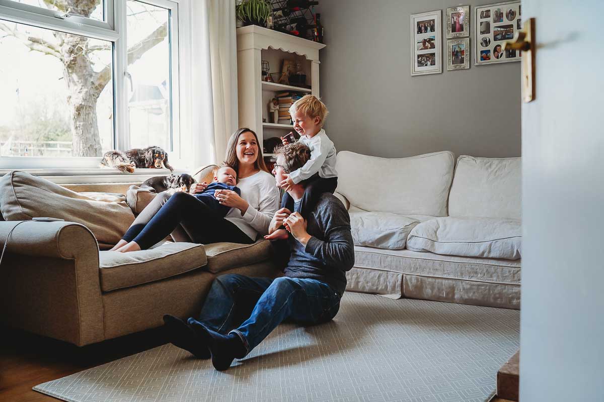 a family sat in their lounge in Newbury posing for a newborn photographer