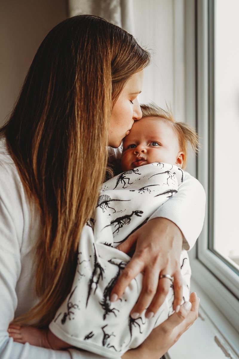 an in-home newborn photoshoot with a mother cuddling her baby 