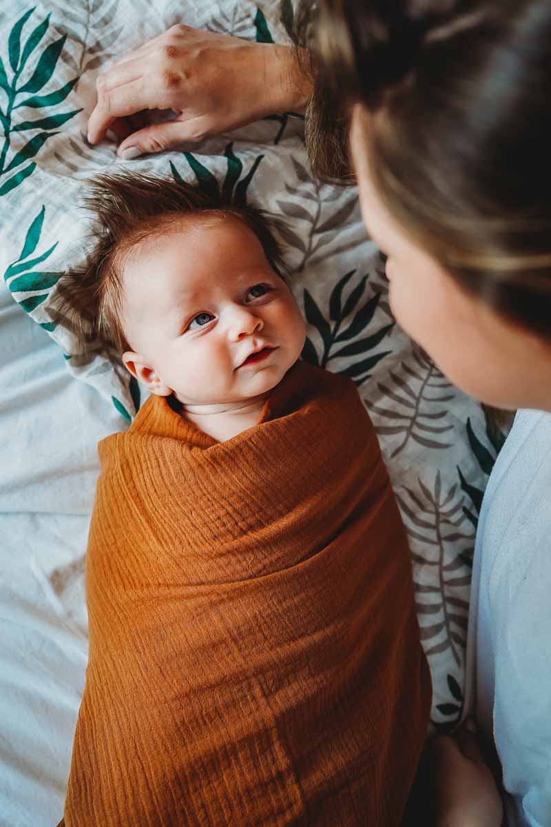 a newborn baby looking up and his mum during an in home photography session in newbury berkshire