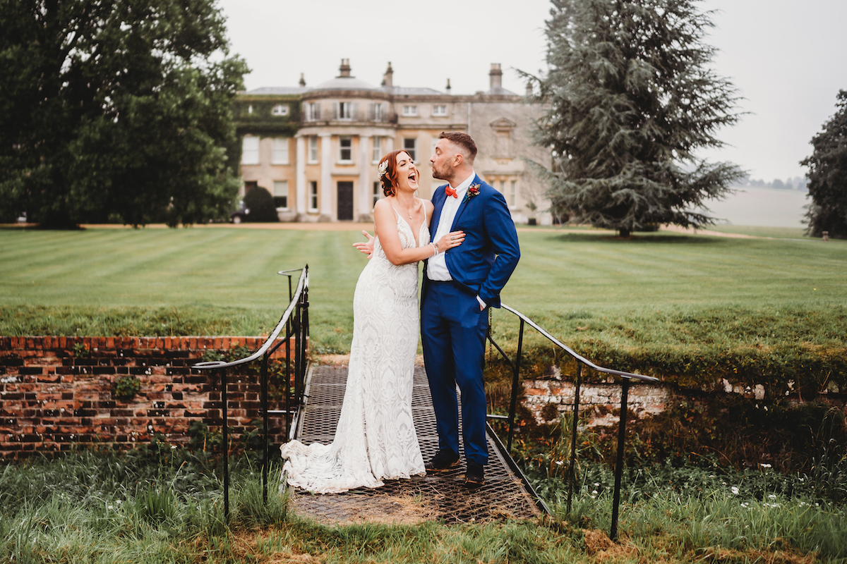 a newly married couple posing for photos in front of a stately home