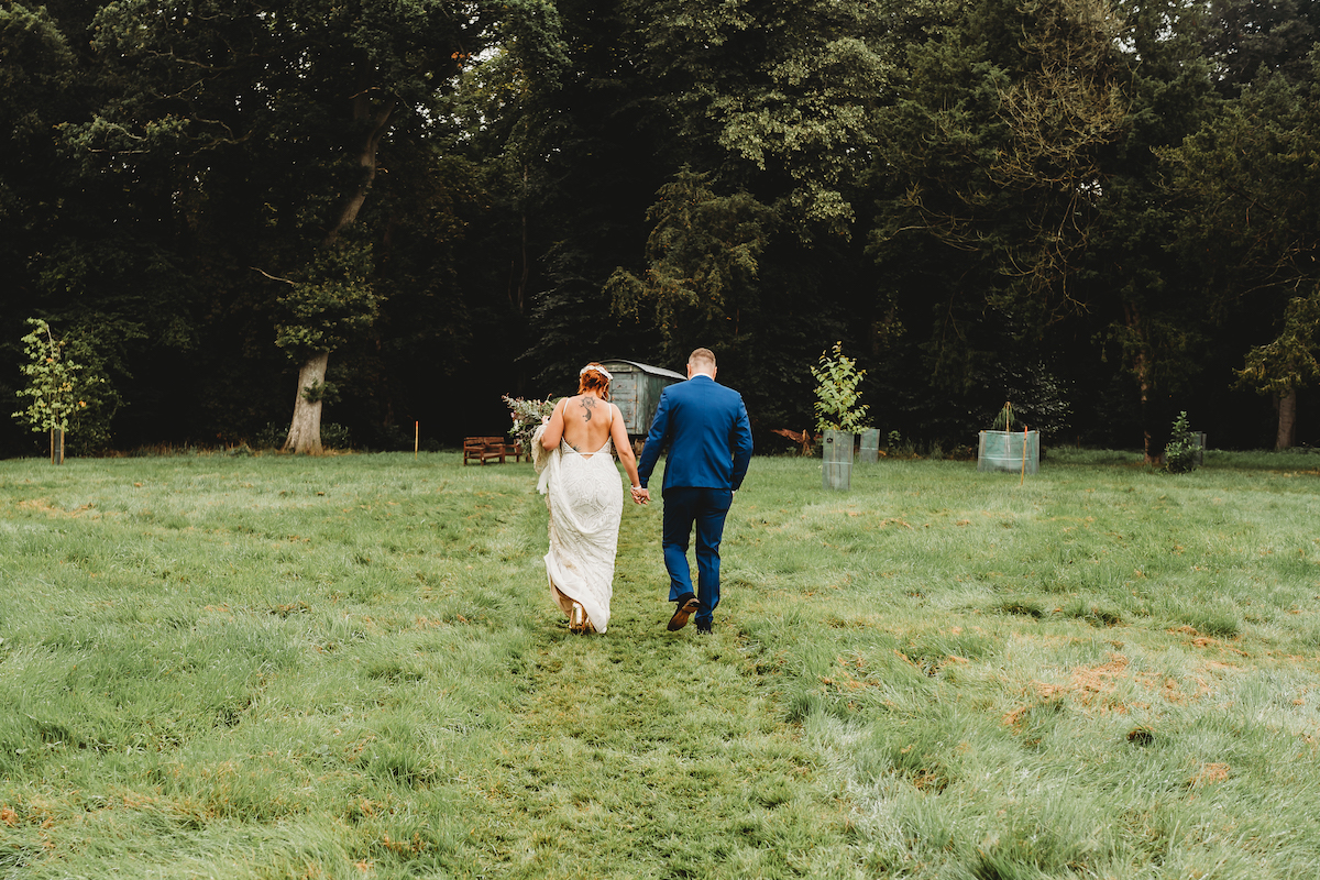 a newly married couple walking away holding hands taken by a newbury wedding photographer