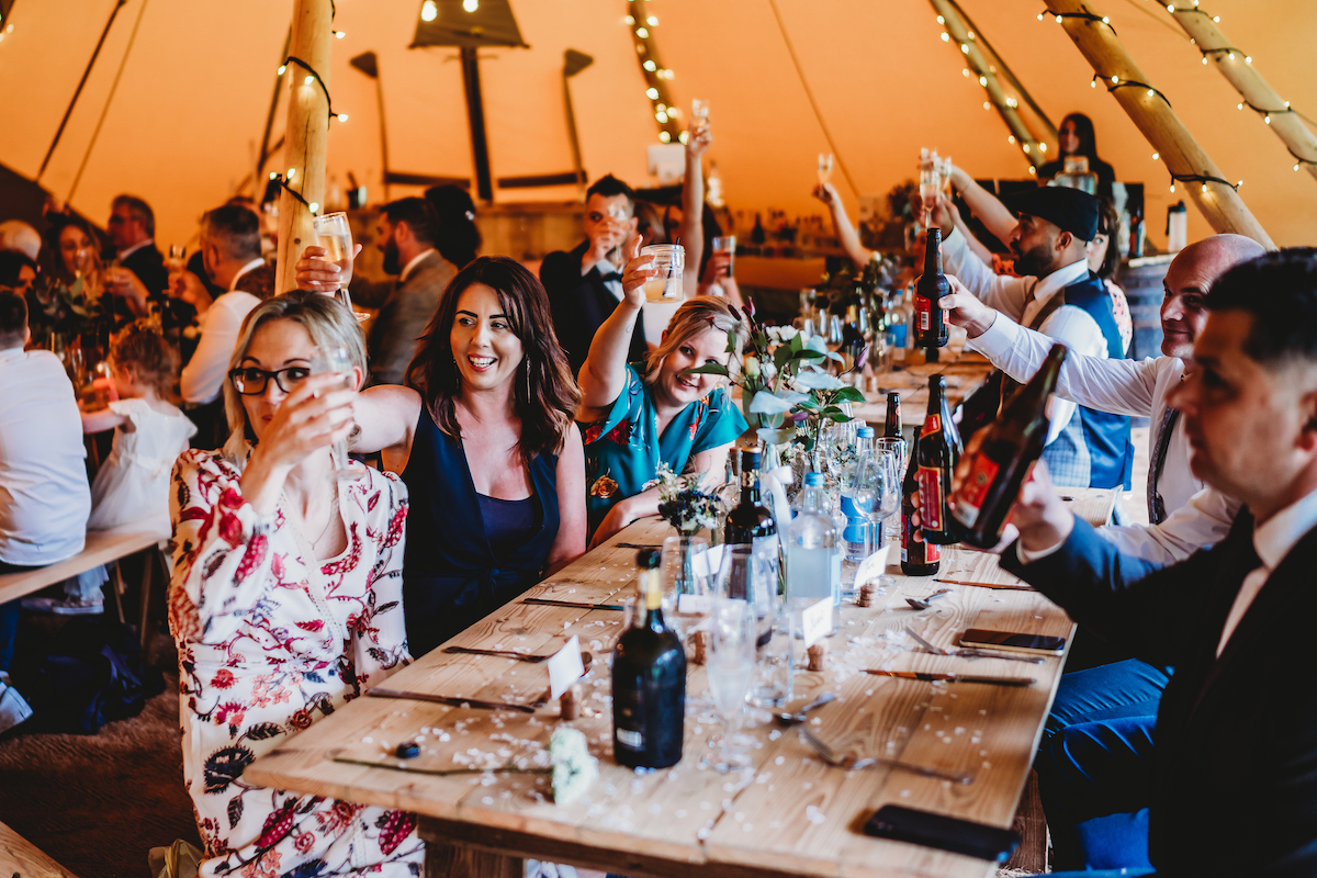 wedding guests celebrating and raising their glasses during a wedding