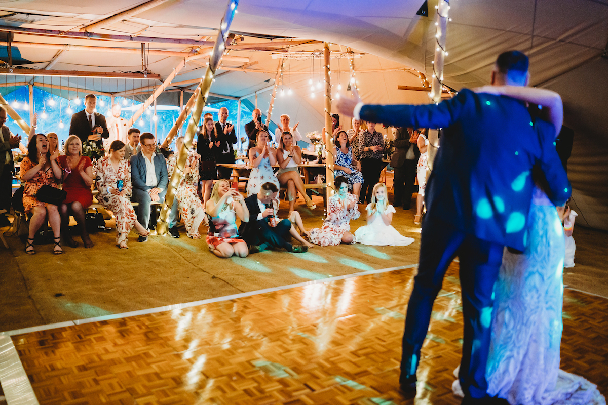 a bridal party watching on as the bride and groom have their first dance