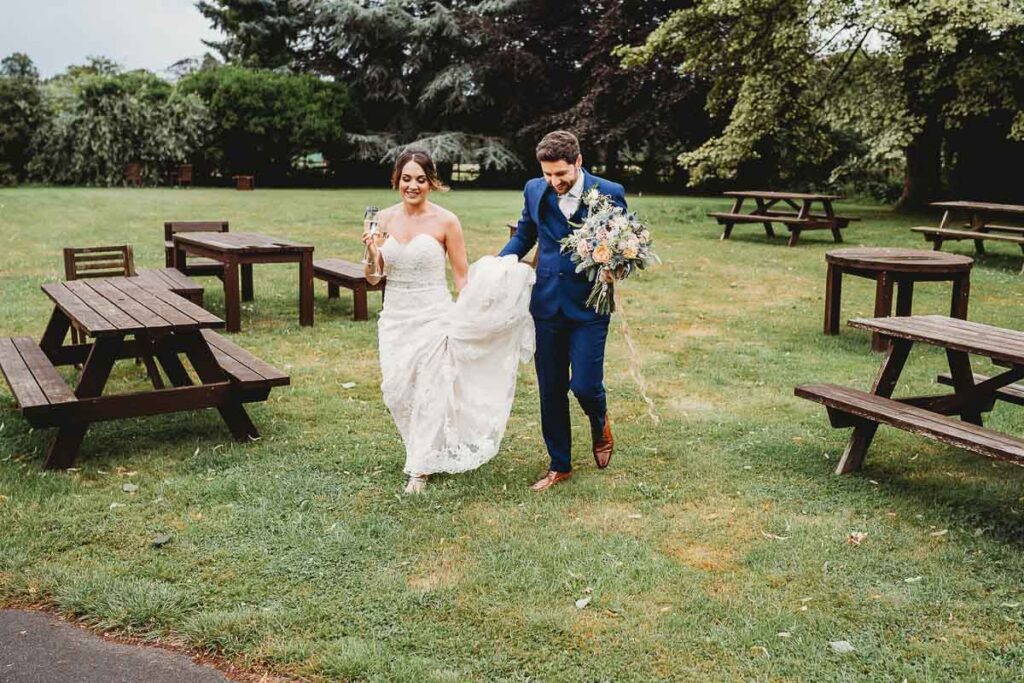 groom helping his bride with her dress at Barn wedding venue 