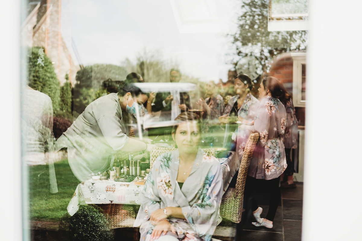 reflection through a window of the bridal party getting ready before a wedding in Newbury