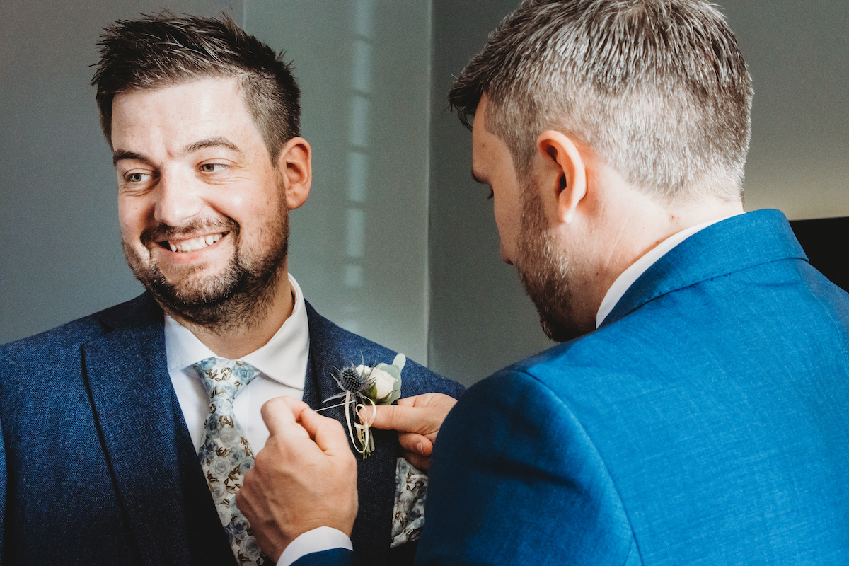 bestman doing the grooms button hole before his wedding