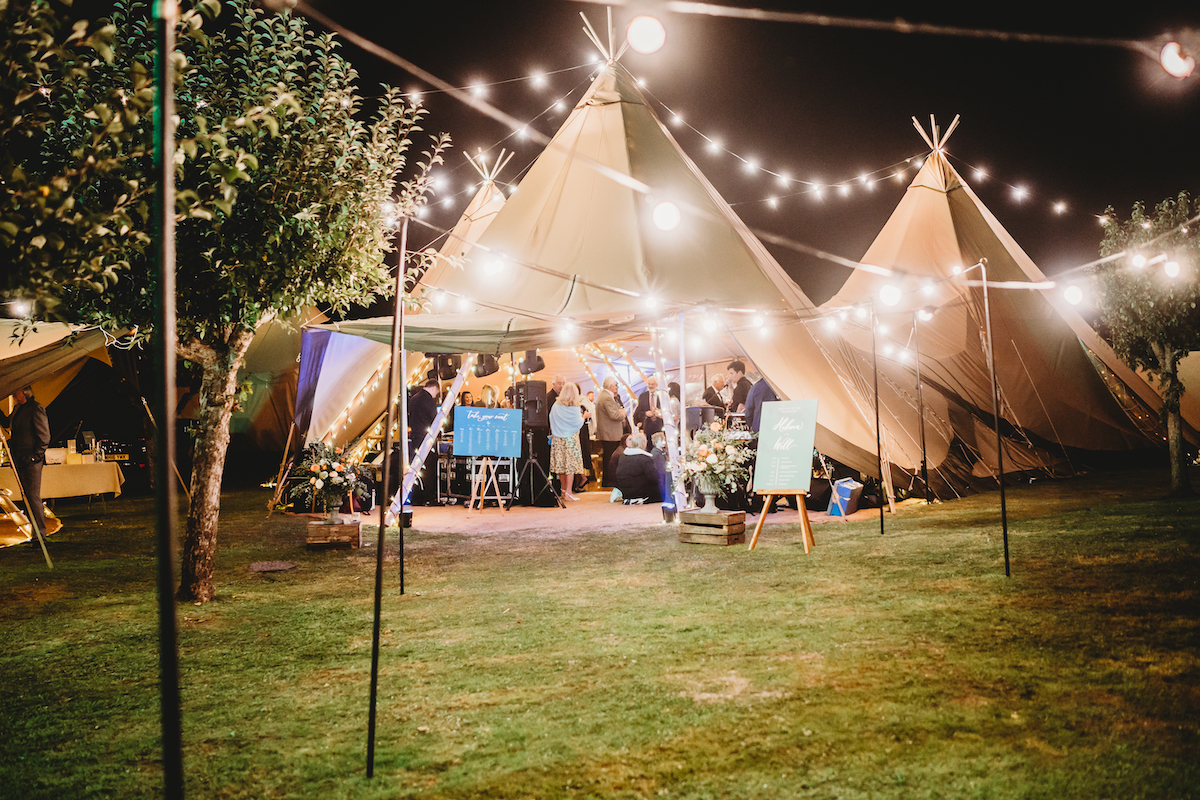 a photo from the outside of the forest edge tipis looking in at a wedding party