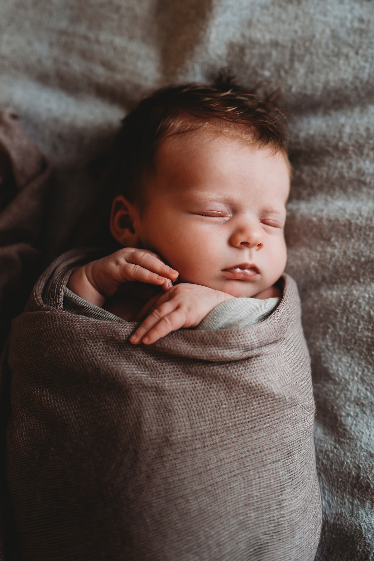 newborn baby cuddled up in a blanket asleep for a baby photographer in newbury