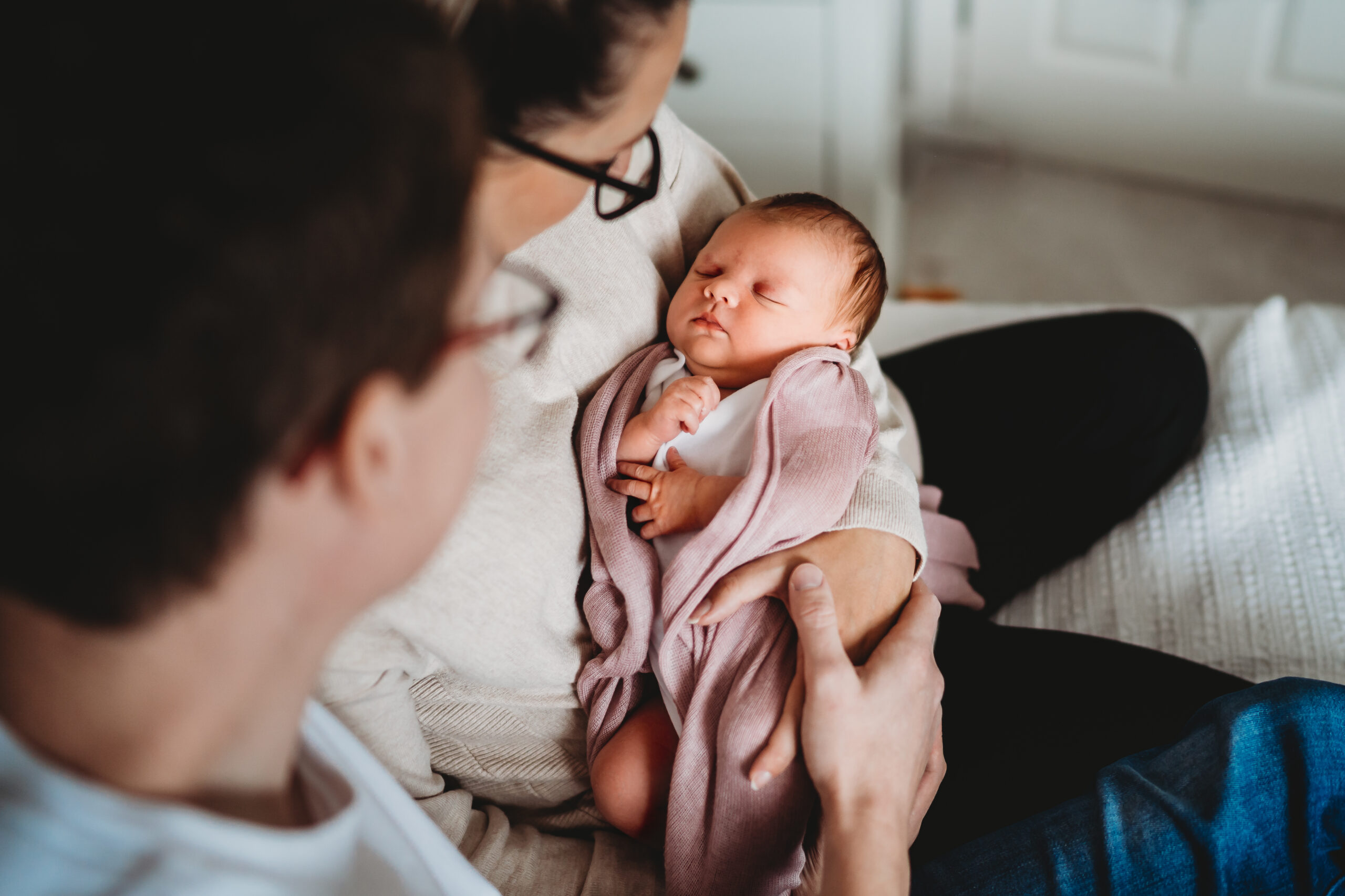 newborn baby asleep in her parents arms for a newbury newborn photographer