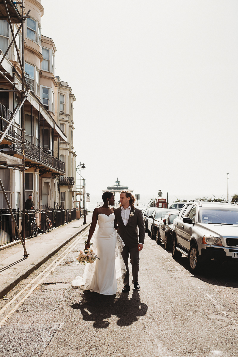 a couple walking through the streets of Brighton after their city elopement. Holding hands looking at each other