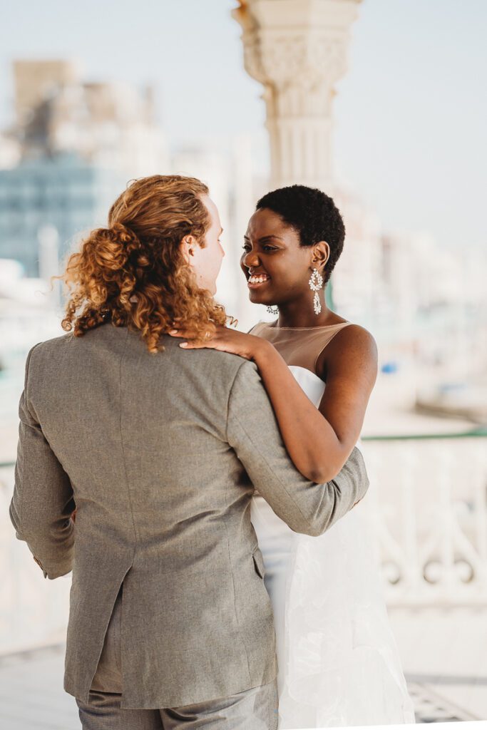 a newly wed couple dancing on brighton pier whilst they giggle