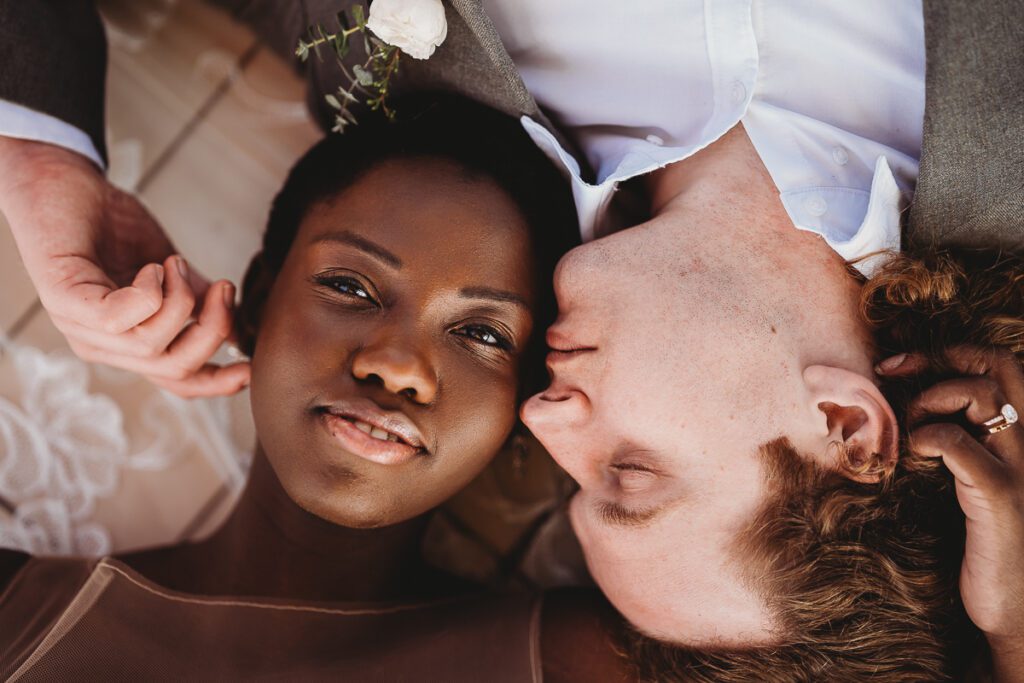 an ariel shot of a bride and groom laying on the floor the bride looking at us, the groom looking at her