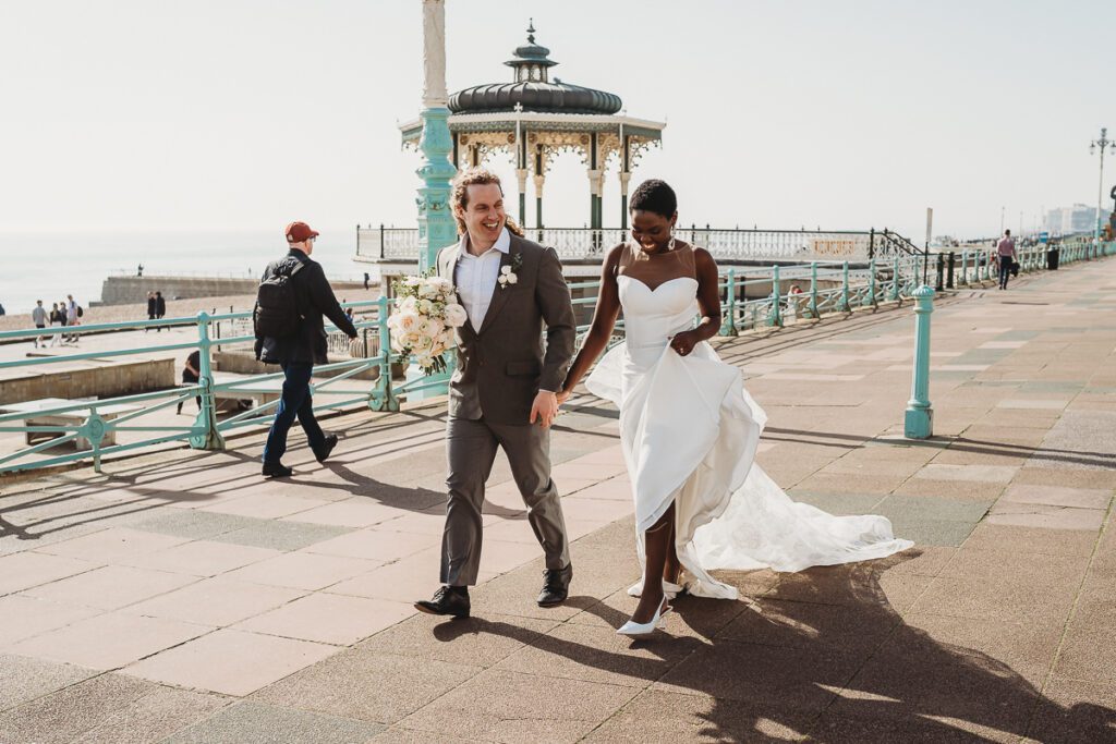 a bride and groom walking down brighton seafront after their city elopement