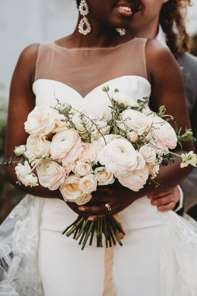 a beuatiful wedding bouquet filled with white and light pink flowers, held by a bride