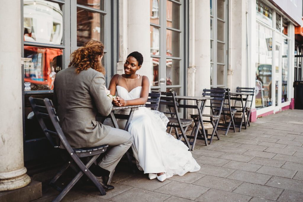 a bride and groom sat outside a cafe waiting for a drink after their Brighton City elopement