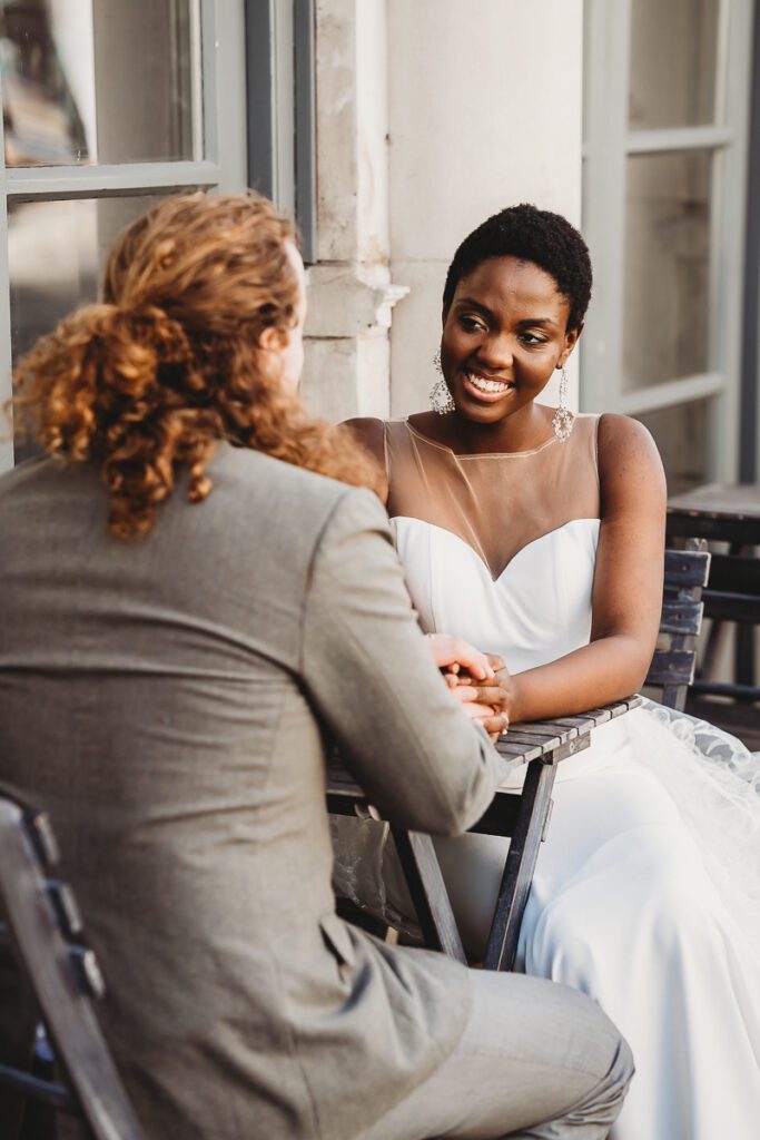 a newly married couple holding hands sat outside a brighton coffee shop after their elopement