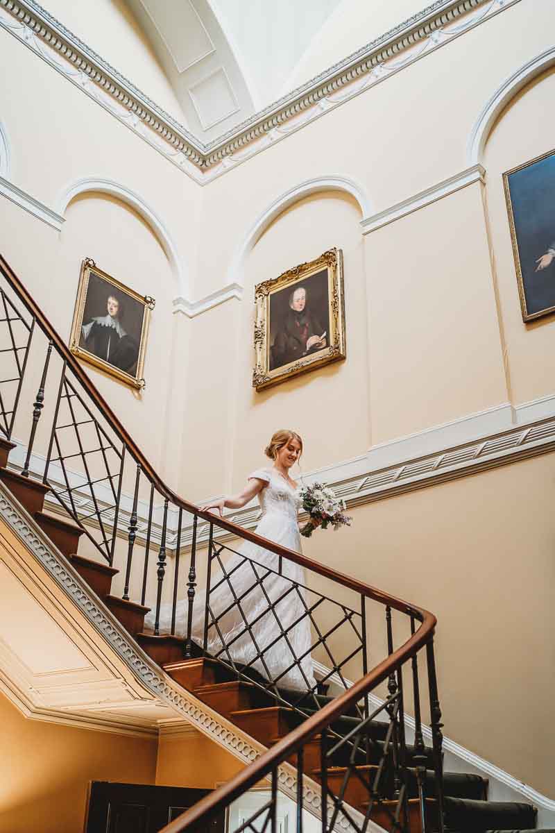 a bride walking down a grand set of stairs at woolley park estate for her tipi wedding 