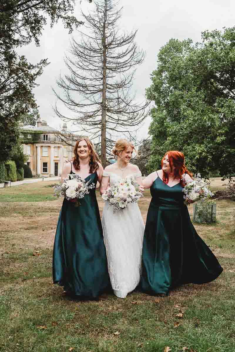 a bride walking with her bridesmaids with woolley estate in the background, for a oxfordshire wedding photographer