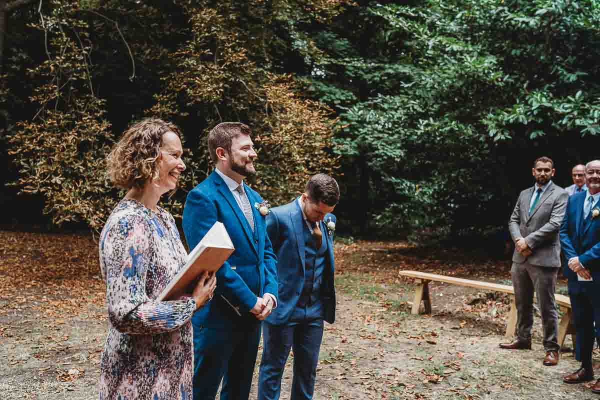 a groom waiting for his bride to appear during their woodland ceremony for their tipi wedding