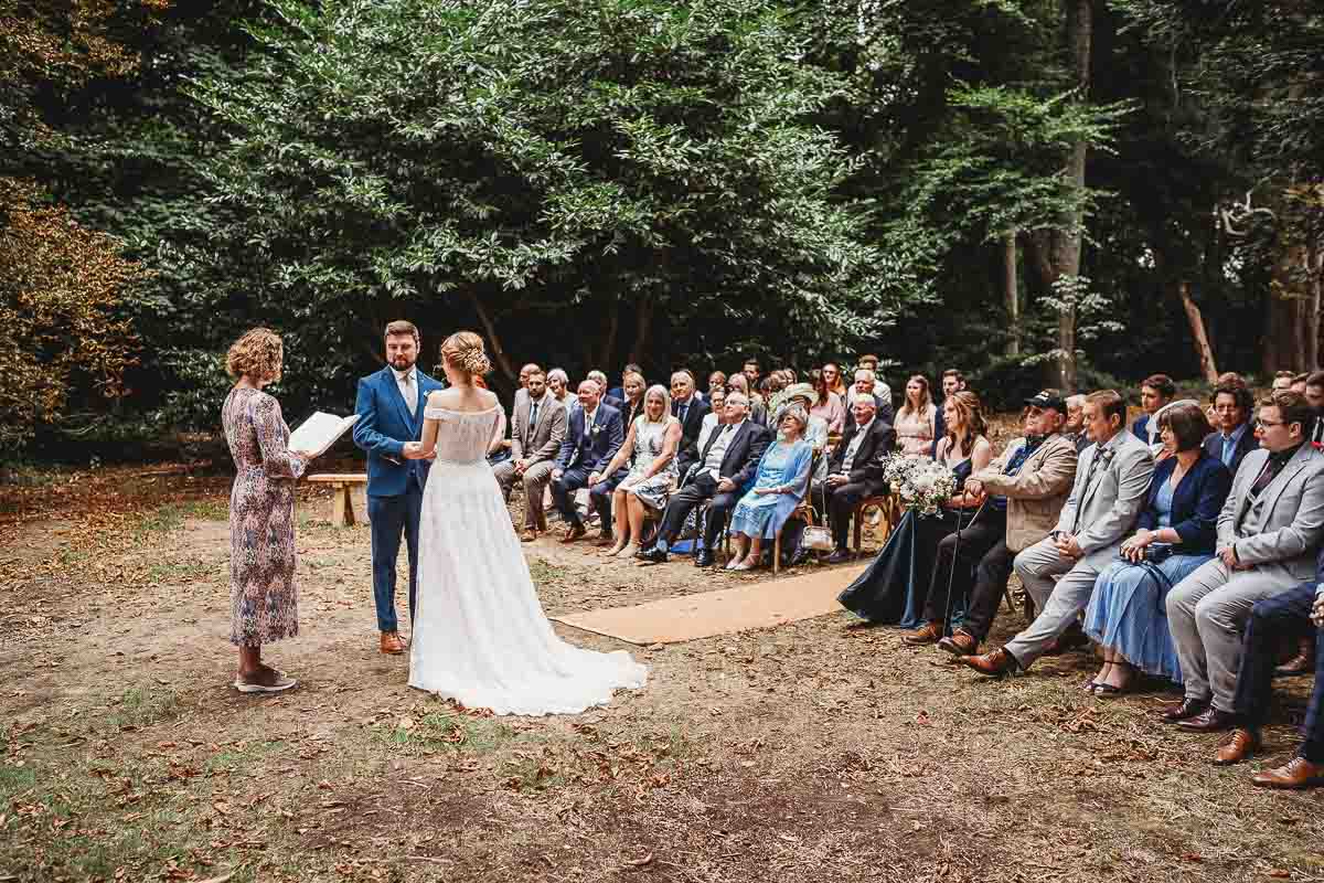 a bride and groom getting married by a celebrant in front of their guests at a woodland ceremony at Woolley Park wedding