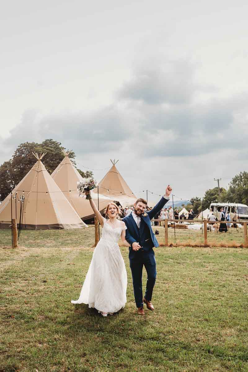 a bride and groom throwing their hands up in the air celebrating their wedding for a berkshire wedding photographer