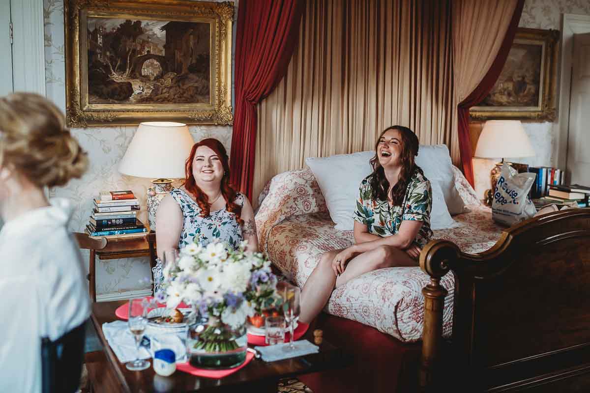 a bridesmaid laughing whilst sat on the bed waiting for the bride to get ready for her tipi wedding in Berkshire 