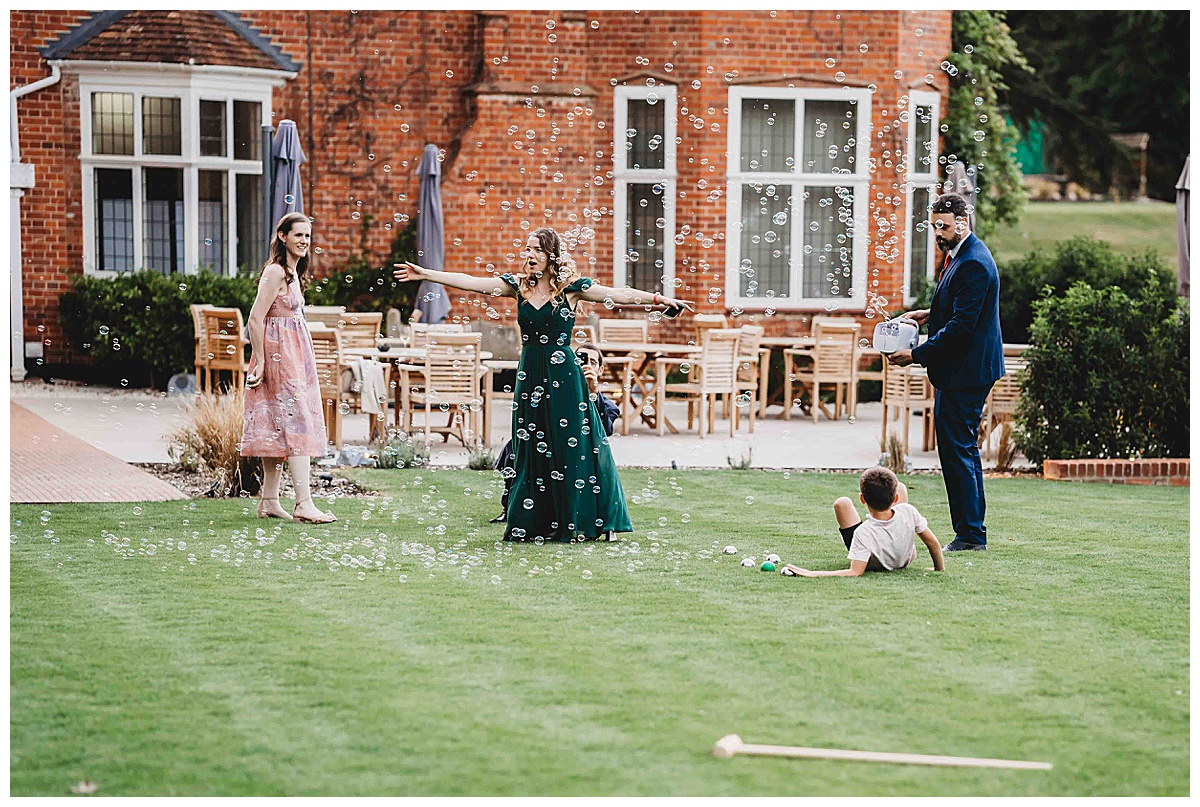 a bridesmaid dancing in the bubbles on the lawn of a wedding taken by a post barn photographer