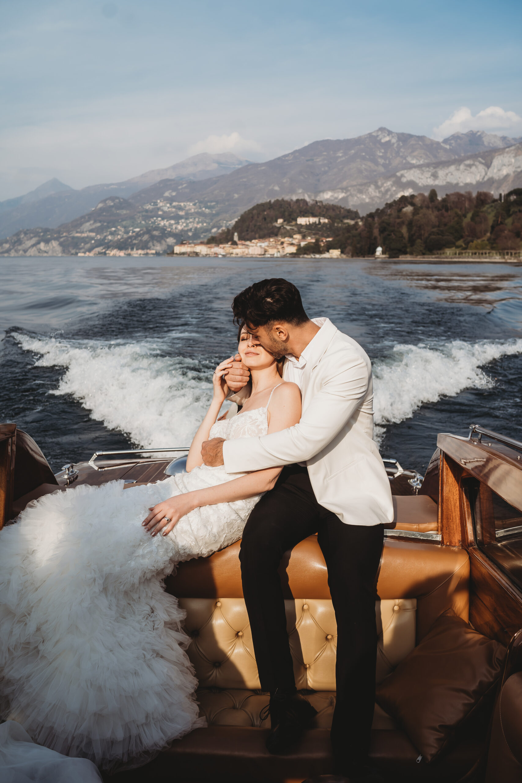 Couple cuddling together as they travel by boat across Lake Como after their wedding in Italy