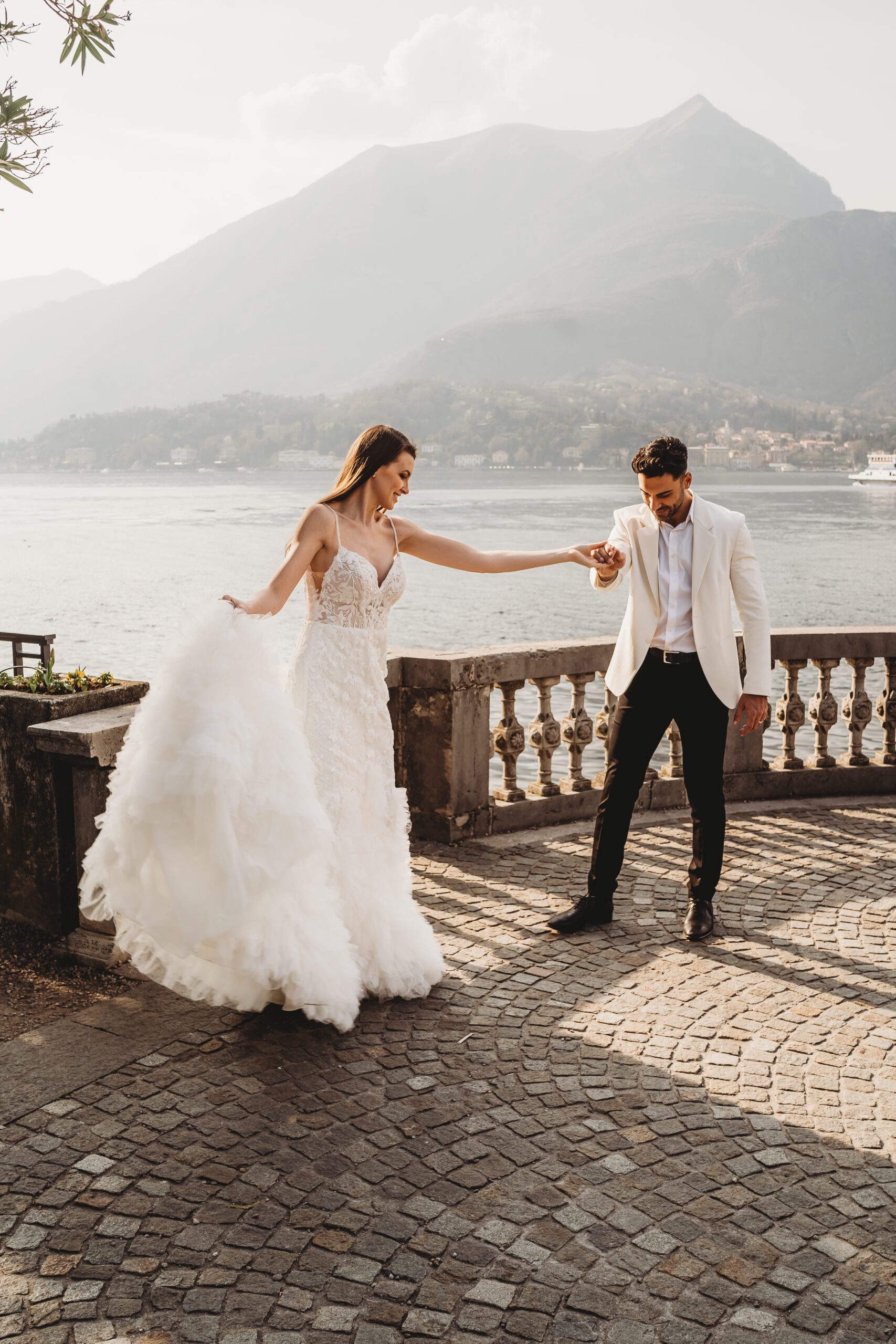 a bride and groom dancing together in front of Lake Como