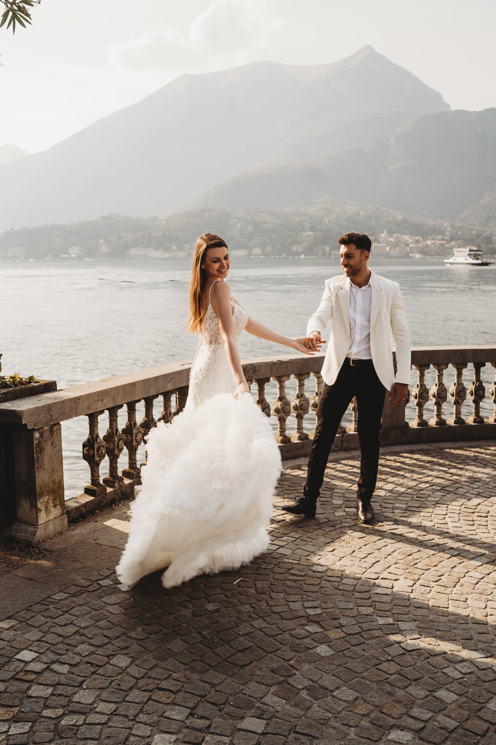 a bride and groom dancing with views of lake como