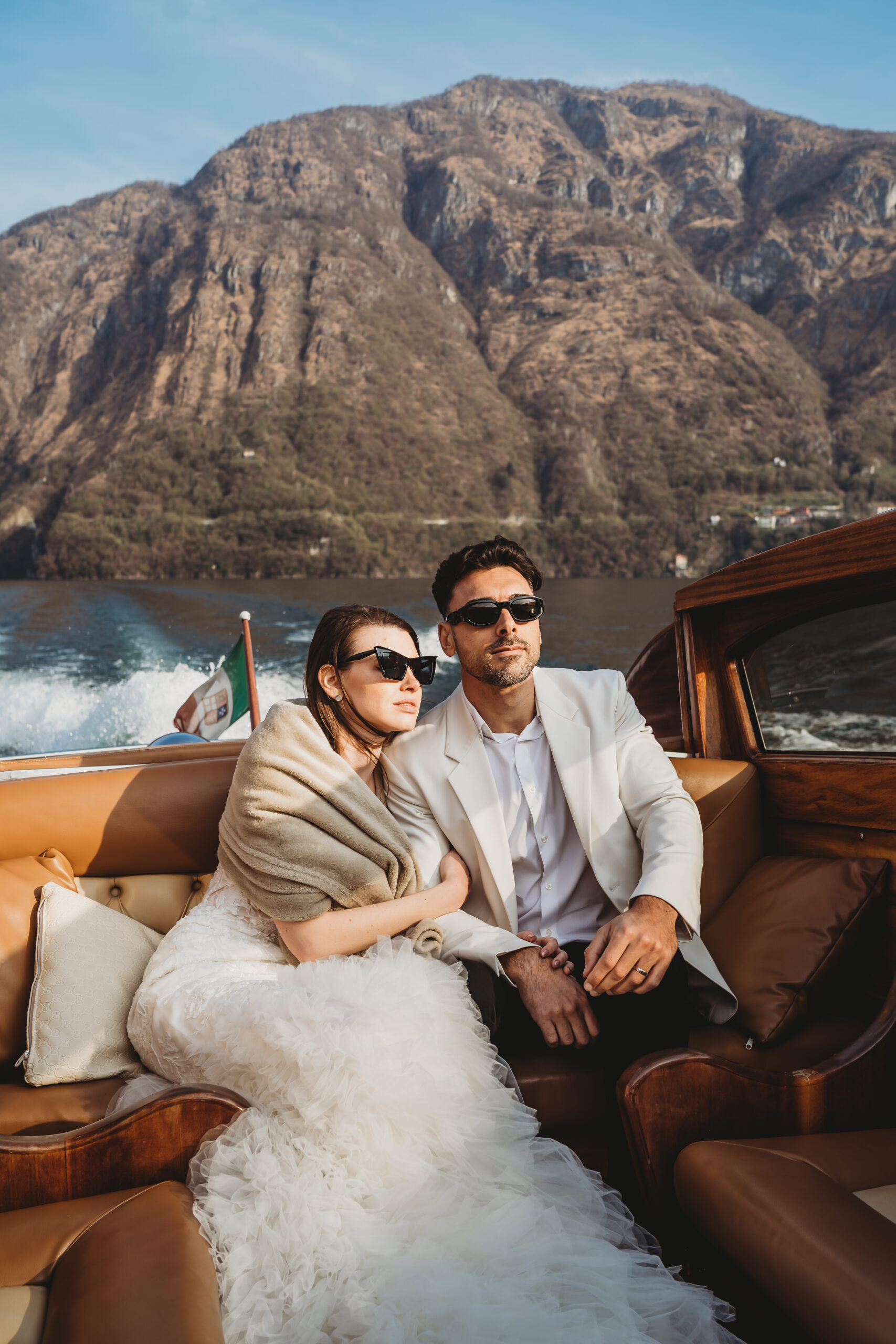 a bride and groom cuddled up together as they take a boat ride across lake como