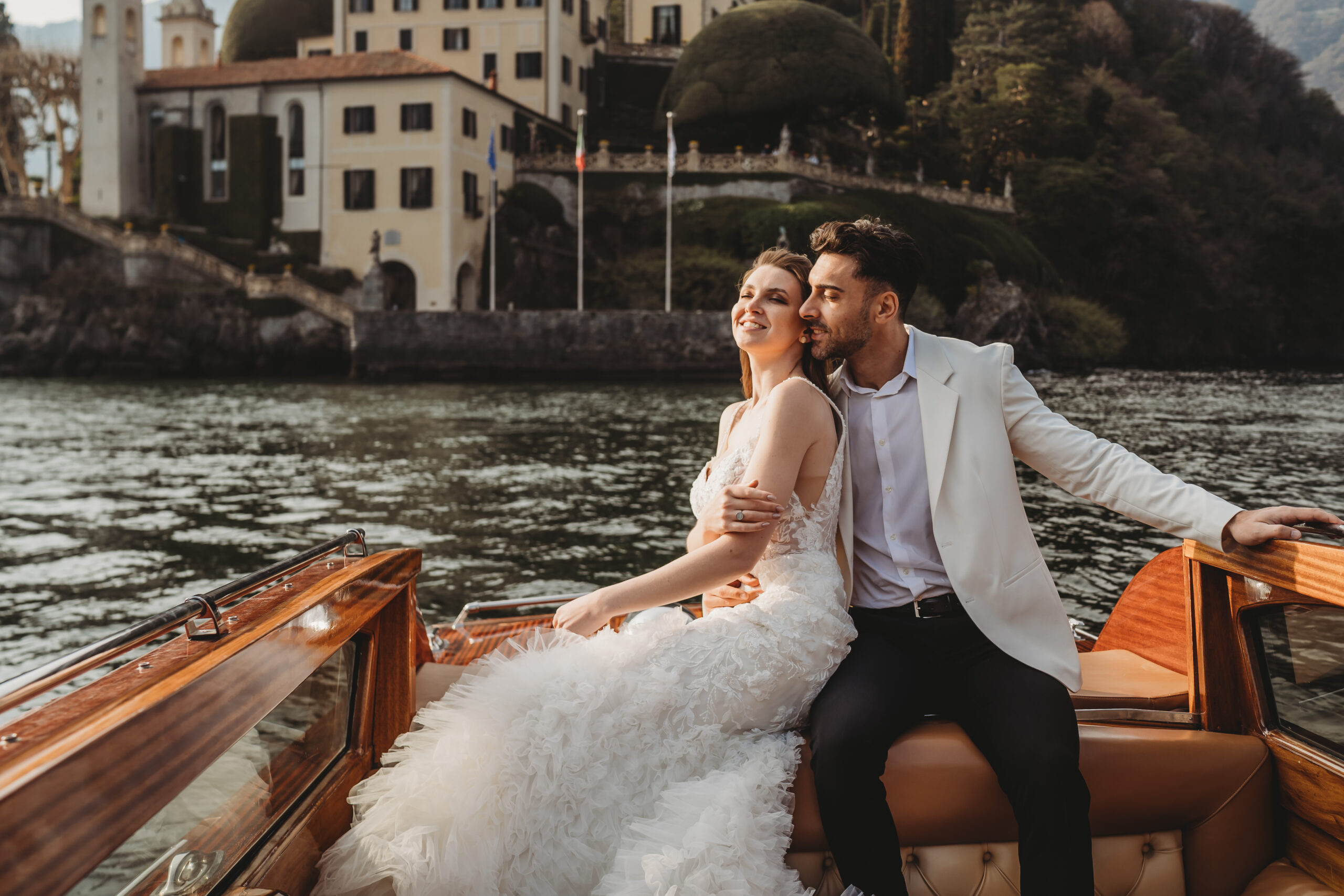 bride and groom cuddling at the back of an italian luxury boat across lake como