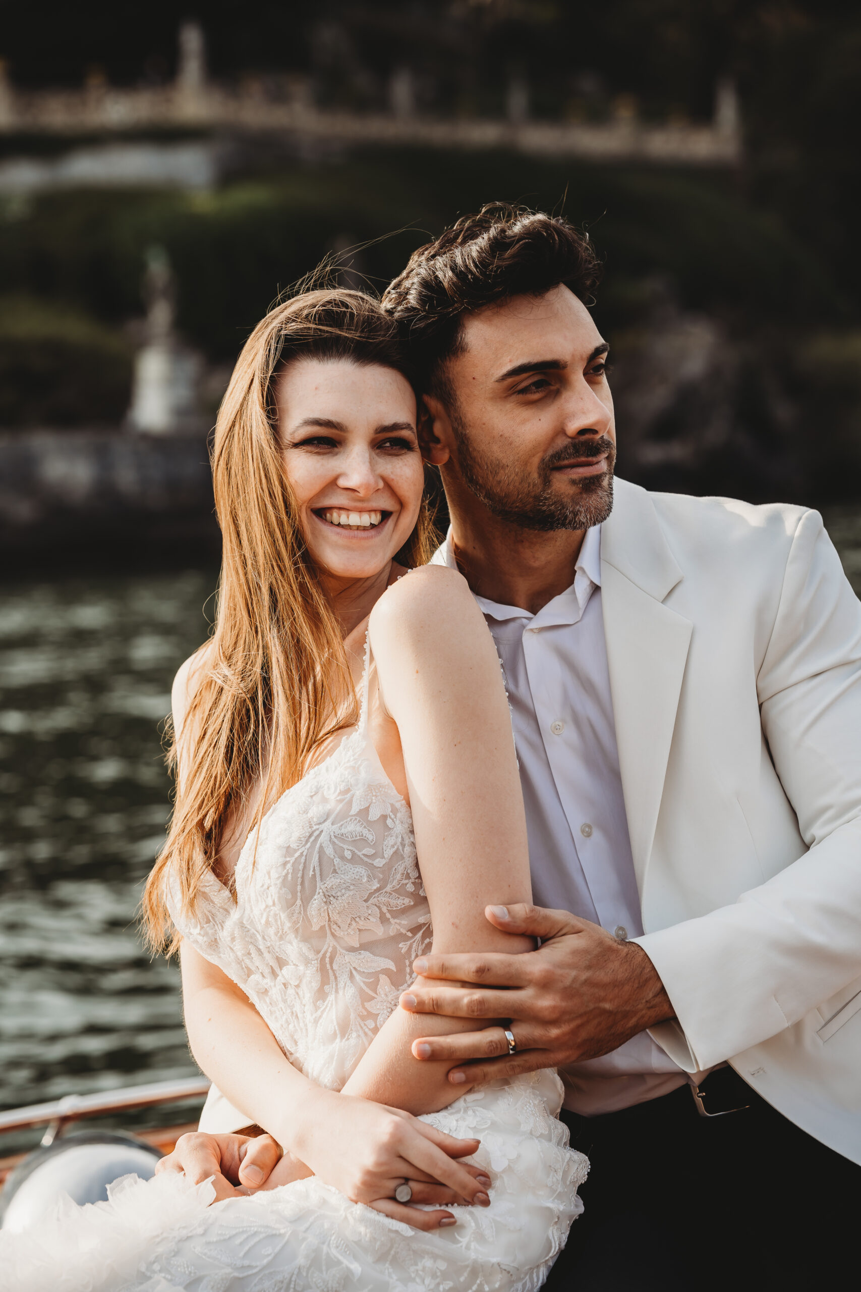 a newly wed couple hugging and enjoying their boat trip across lake como taken by a lake como wedding photographer 