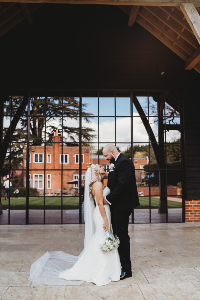 newly wed bride and groom in front of the big windows at the post barn newbury