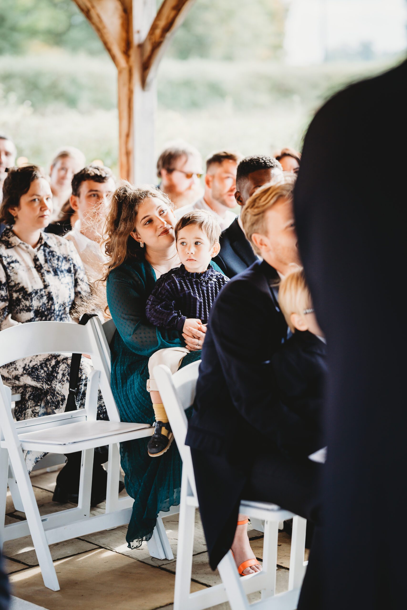 hampshire wedding photography of a little boy sitting on his parents lap during a wedding 