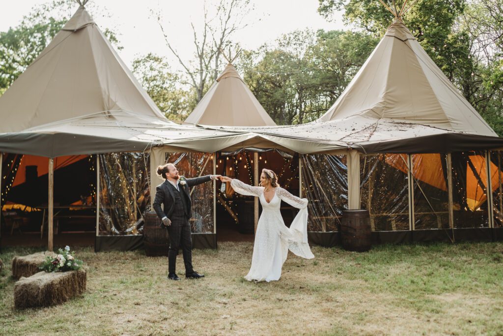 a groom dancing with his new wife in front of the tipis for a Festival wedding photographer 