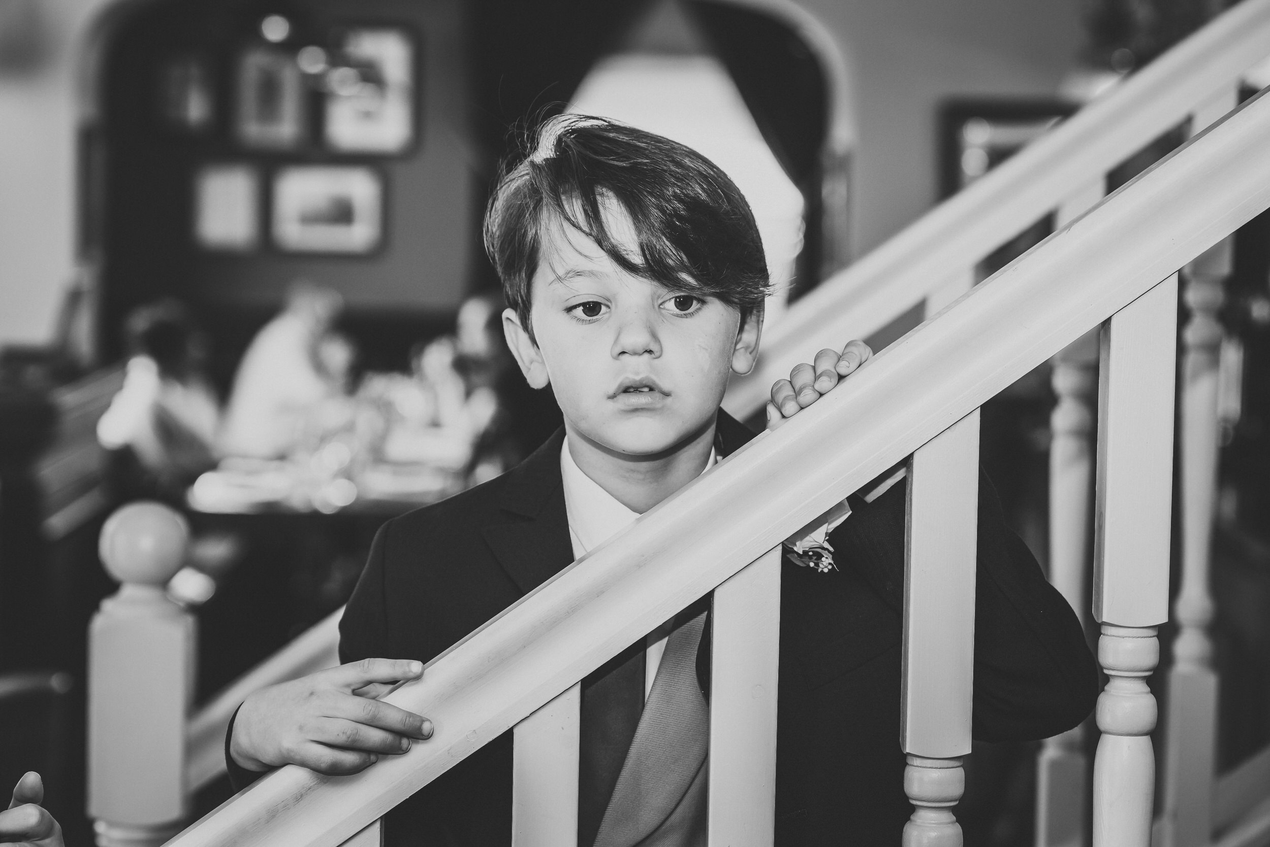 a page boy looking over a stair banister before a wedding 