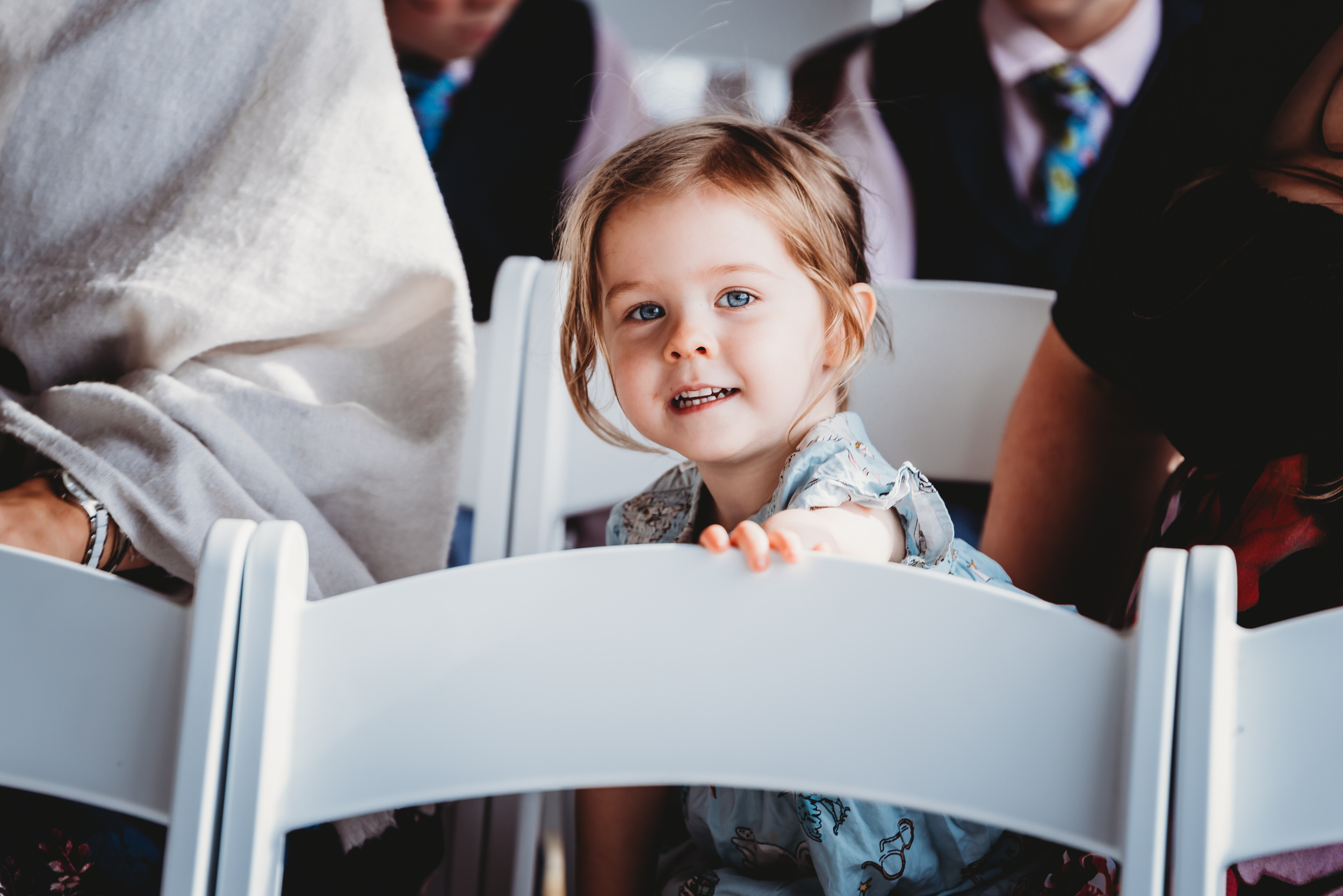 hampshire wedding photography of a child guest looking over a chair before a wedding starts 