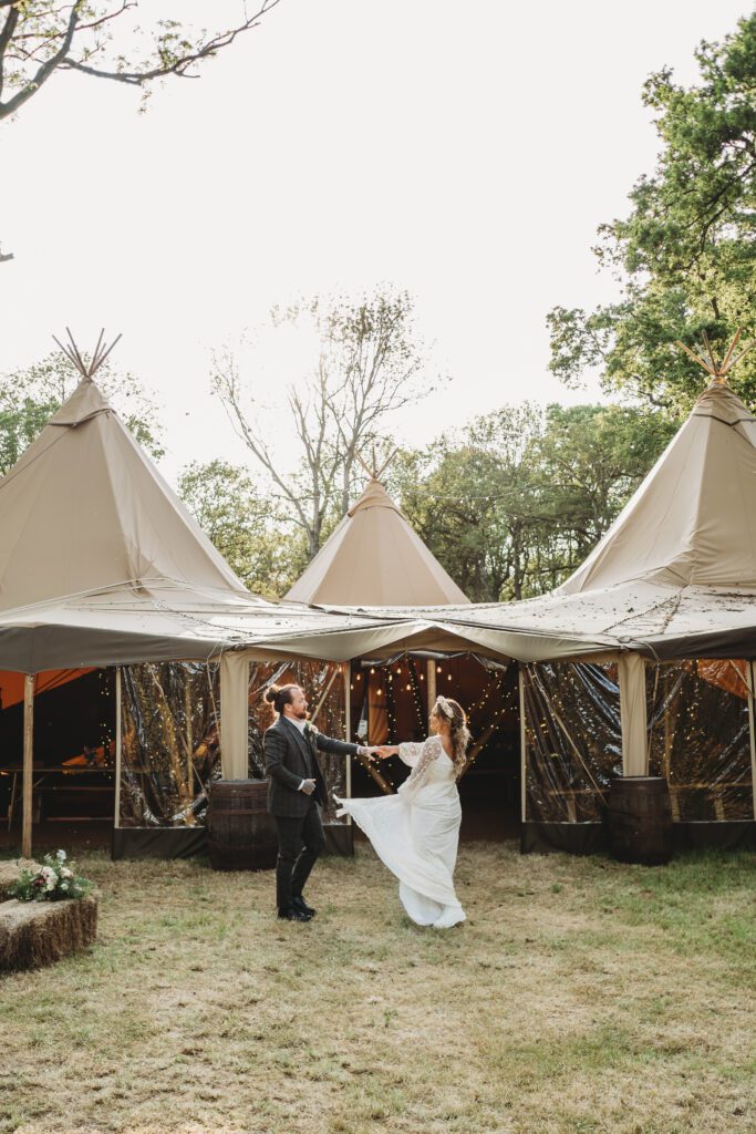 a groom dancing with his new wife in front of the tipis for a Festival wedding photographer 