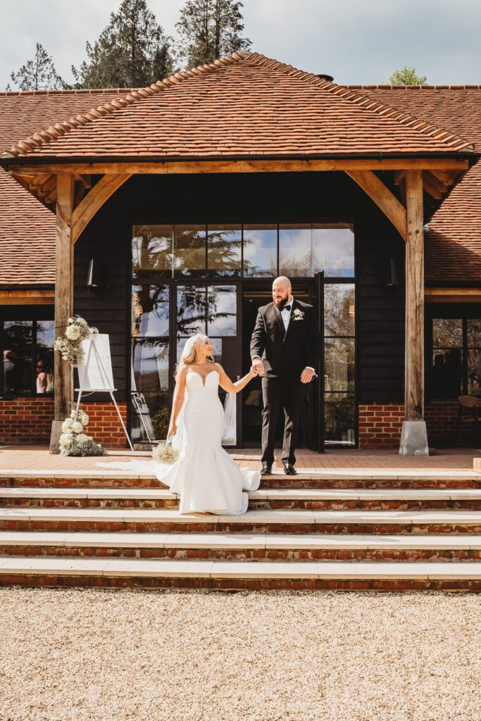 wedding photography of a bride leading a groom down the stairs at the post barn newbury