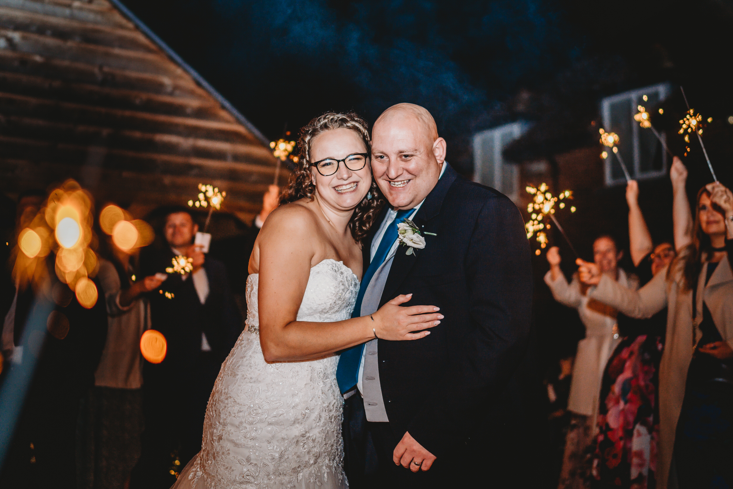 a bride and groom posing  in the middle of sparkler line up taken by a hampshire wedding photographer 