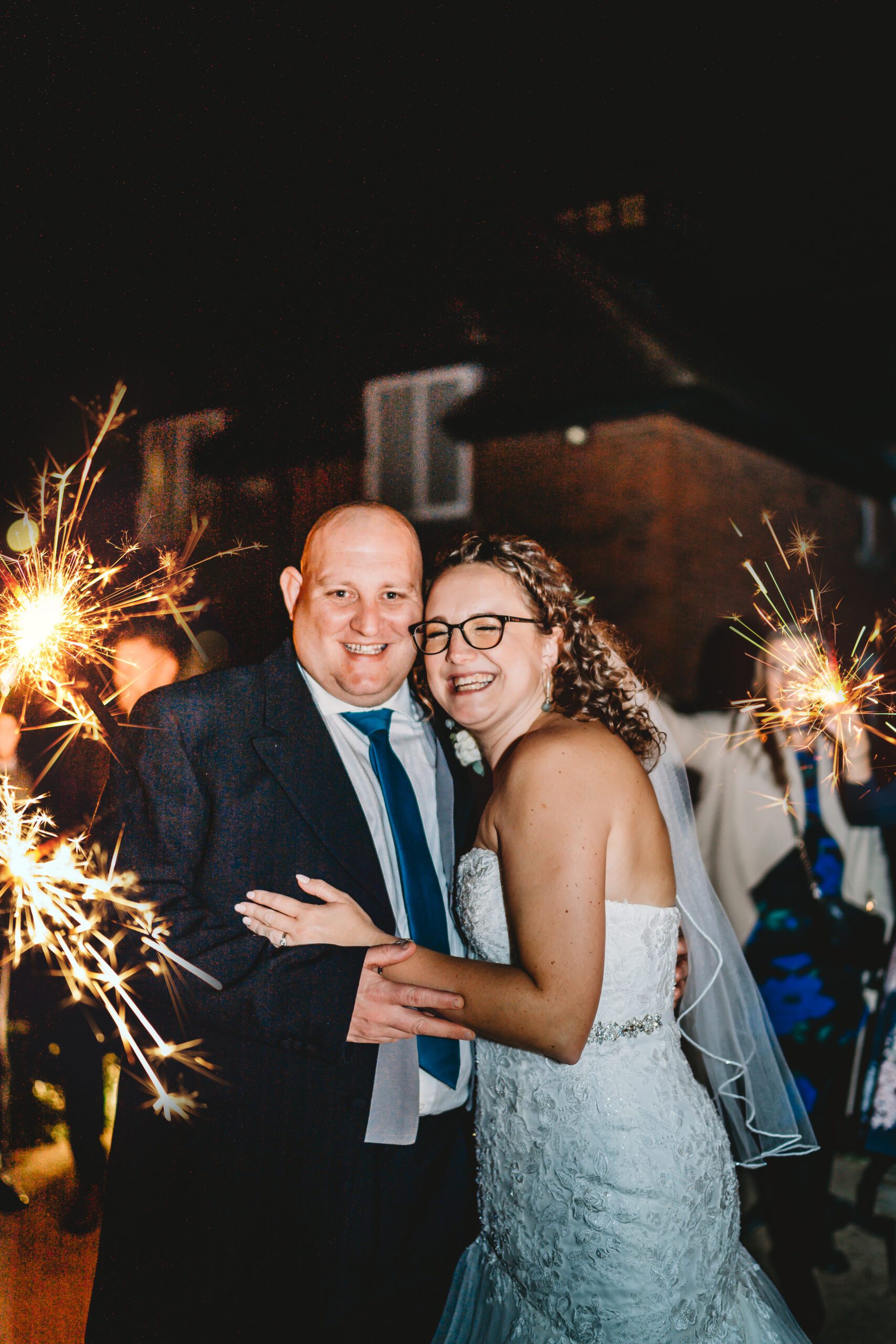 a bride and groom posing  in the middle of sparkler line up taken by a hampshire wedding photographer 