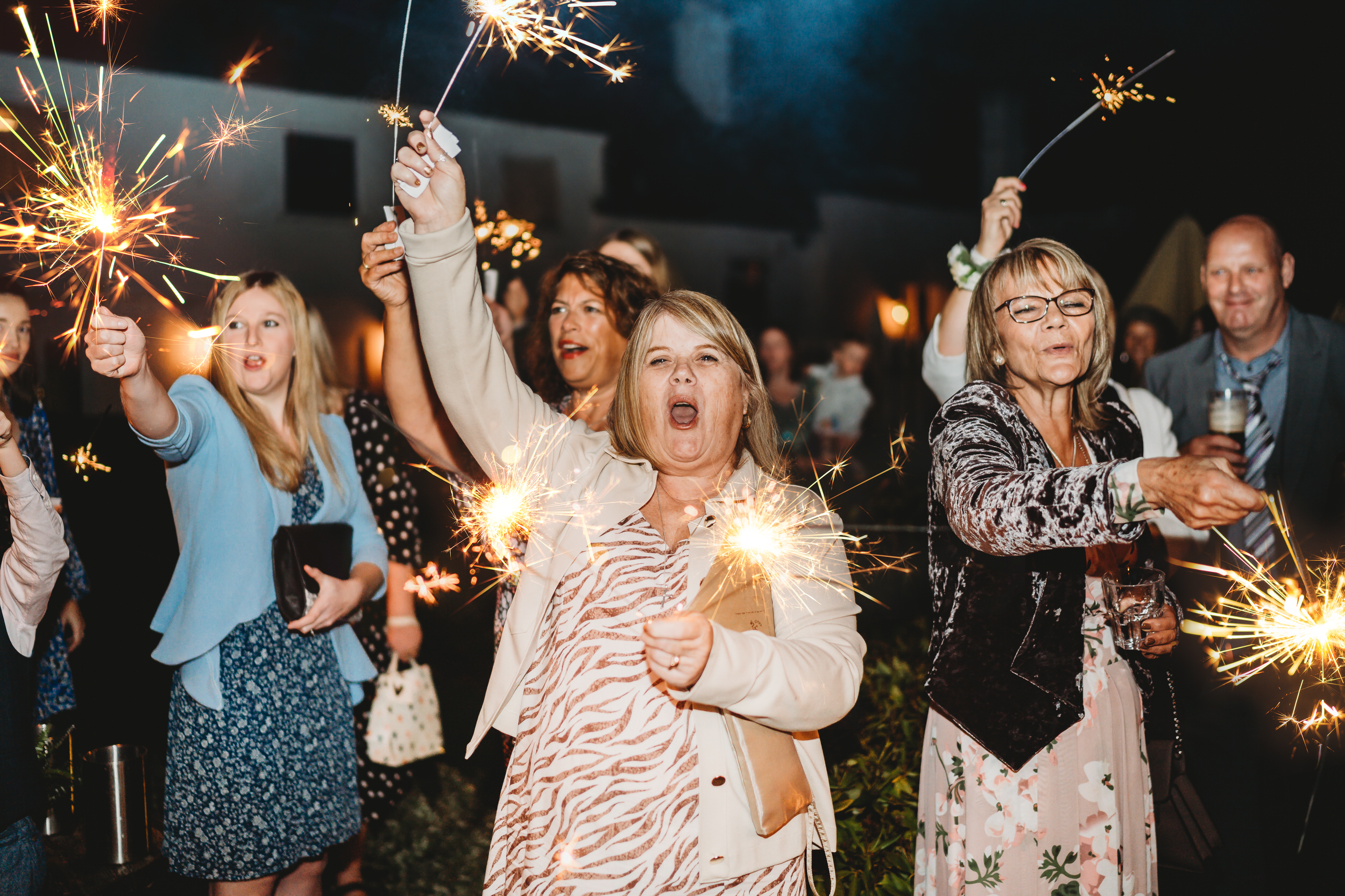 a lady screaming whilst playing with sparklers at a wedding taken by a wedding photographer 